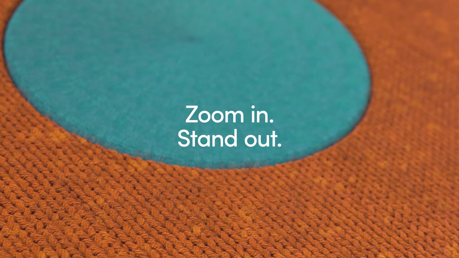 Afbeelding uit de motion graphic: een grove oranje kleurige structuur en een fijnere blauwe structuur met de tekst "Zoom in. Stand out."